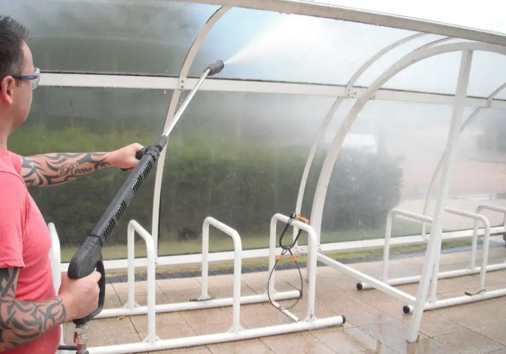 Cleaning the canopy of a cycle shelter with a pressure washer
