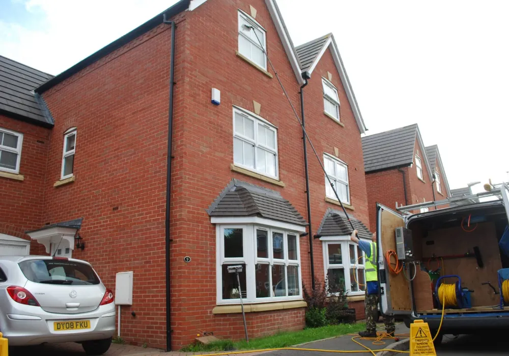 Window cleaning van with hose reels outside a three-storey house